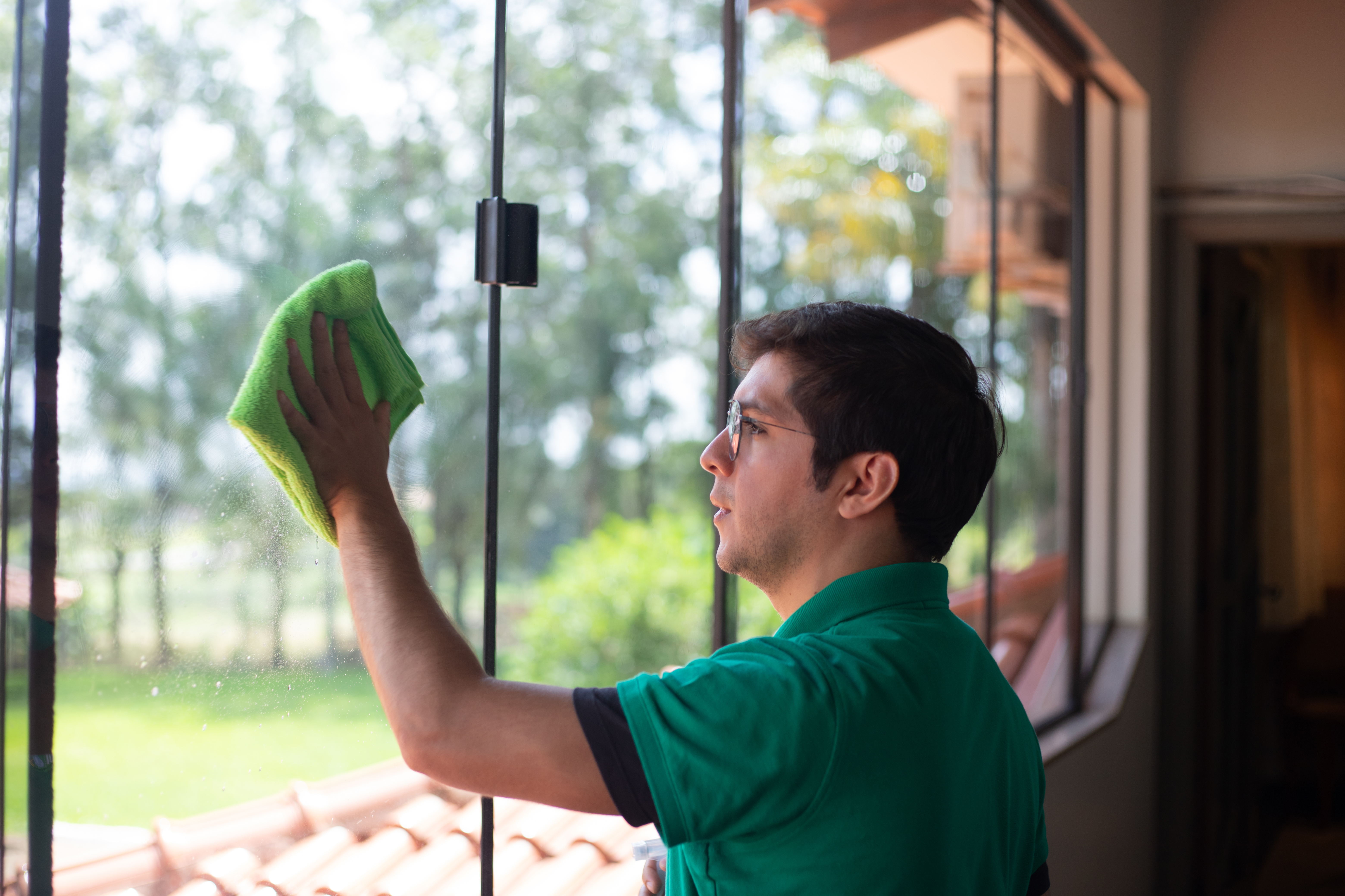 Maid 4 Cleaning professional cleaning a window with a microfiber cloth, demonstrating streak-free results.