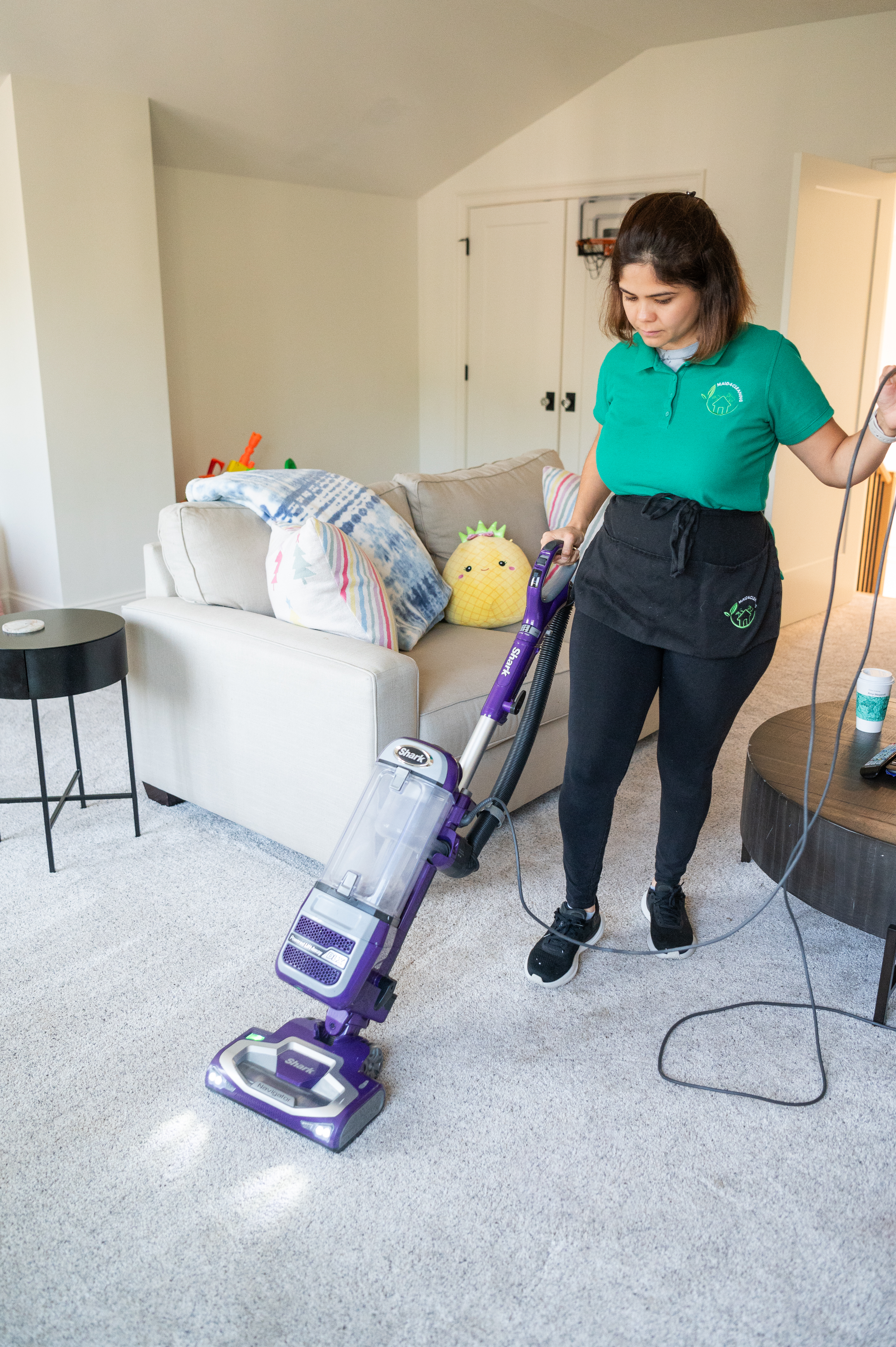 A professional cleaner from Maid 4 Cleaning vacuuming a plush carpet in a cozy living room, ensuring a fresh and spotless home.