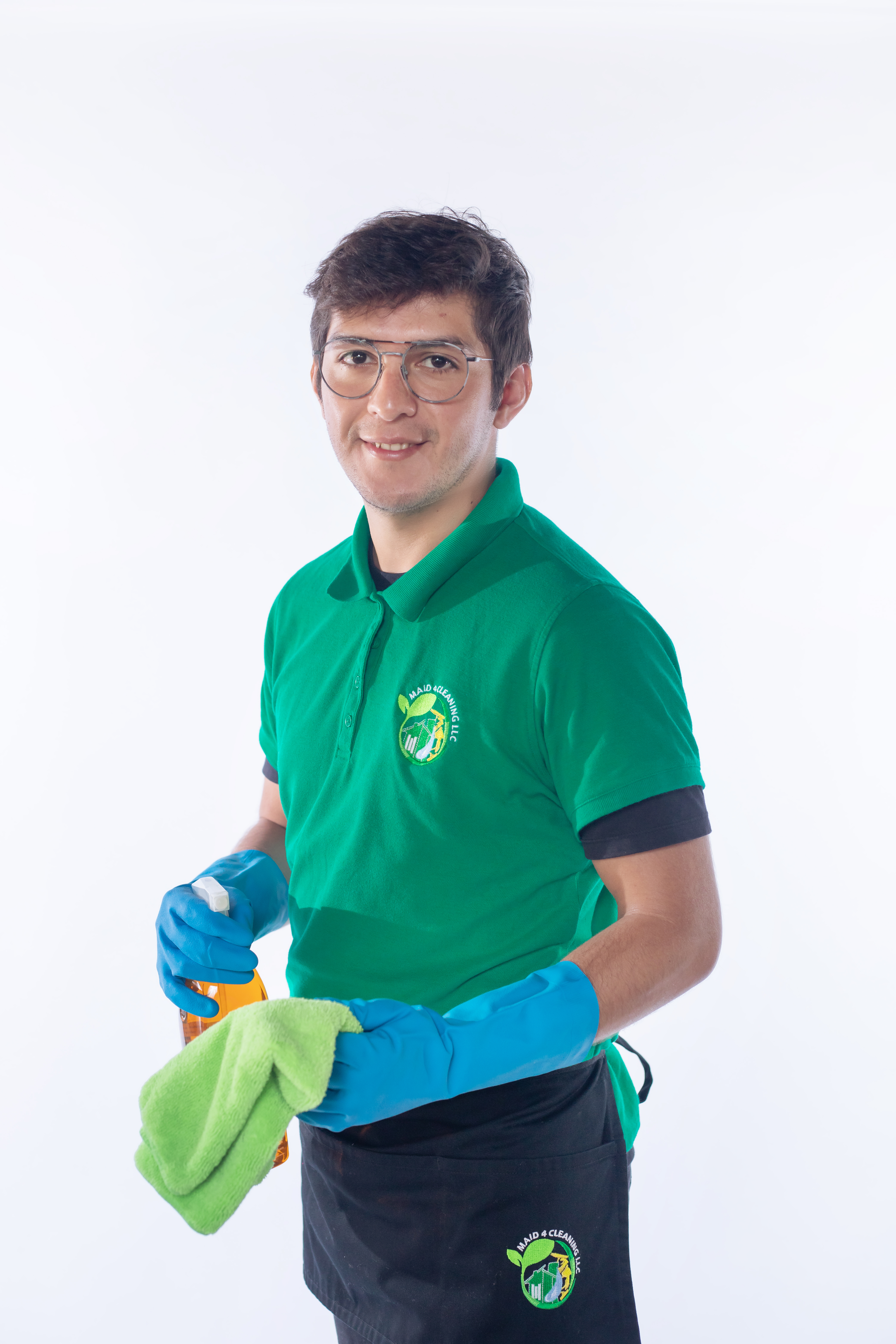 A professional cleaner from Maid 4 Cleaning wearing a green uniform and blue gloves, holding a spray bottle and microfiber cloth, ready to clean—representing expert cleaning services for maintaining a fresh and hygienic home, including pet-friendly spaces like dog beds.