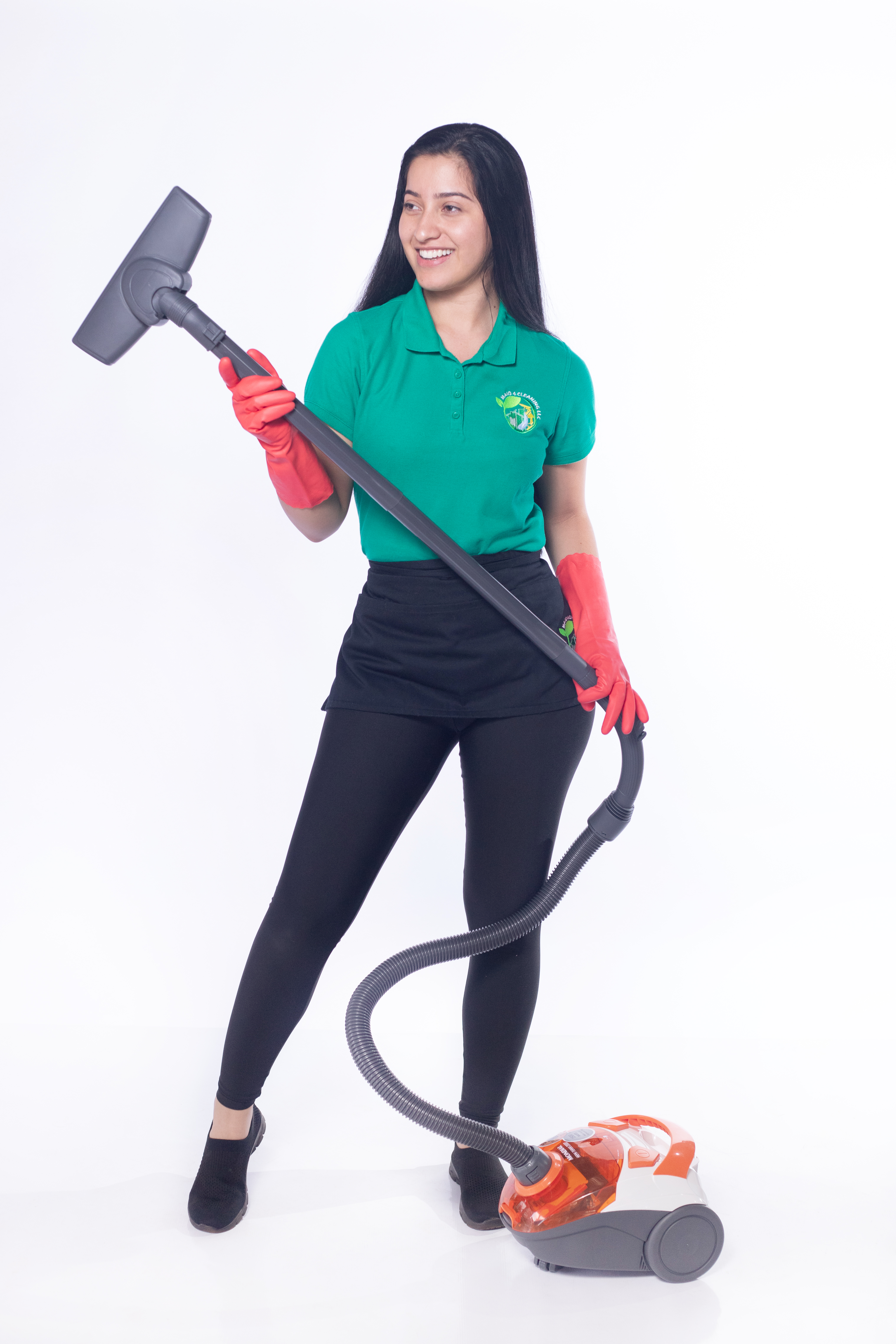 A professional cleaner in a green uniform and red gloves smiling while holding a vacuum cleaner, symbolizing expert pet-friendly cleaning services to remove dog hair and pet odors from homes.