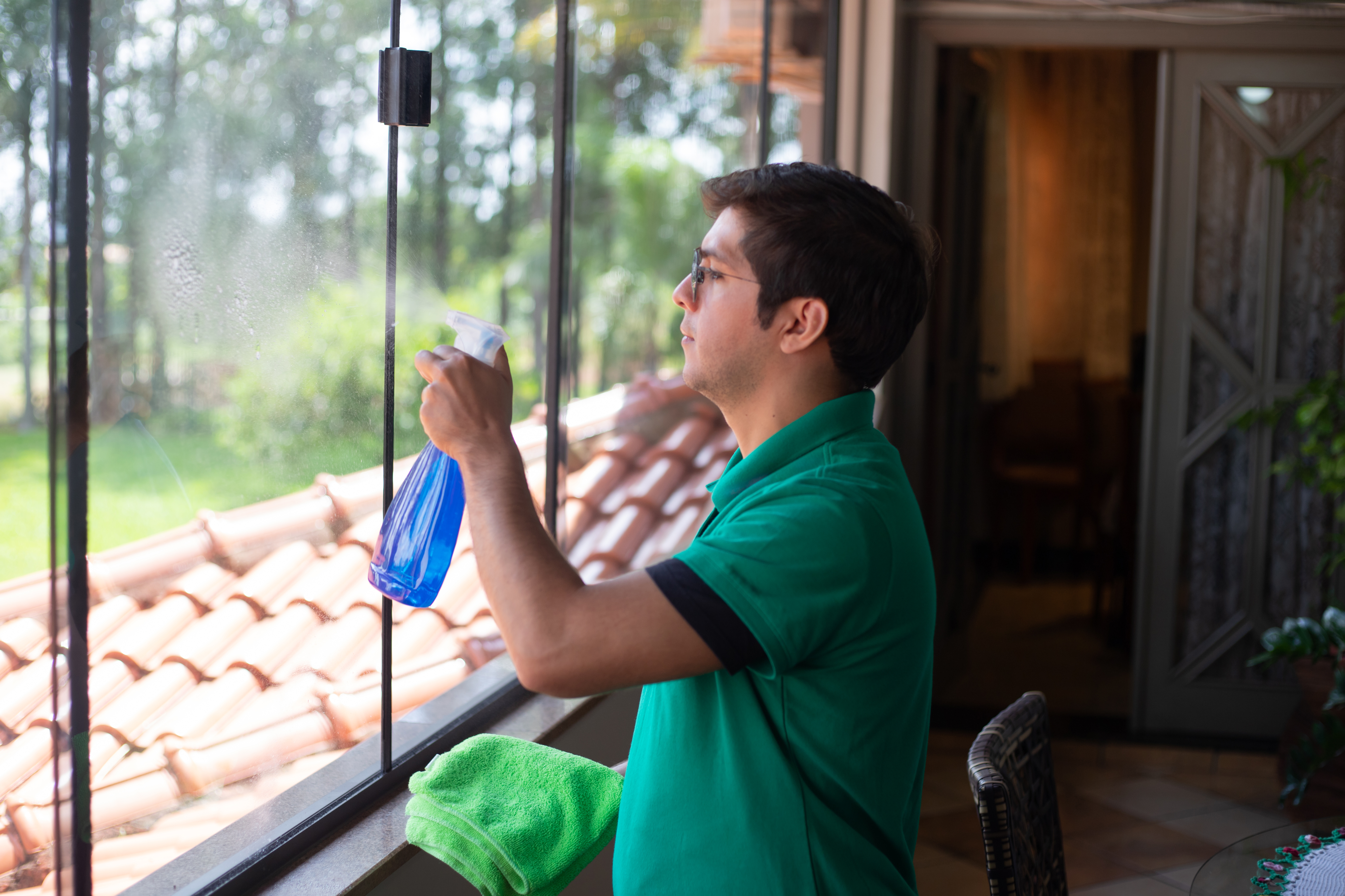 Professional window cleaner using a squeegee to clean a large window, ensuring a streak-free finish.